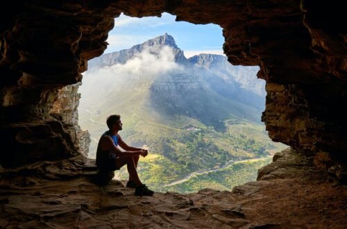 photo of man sitting on a cave